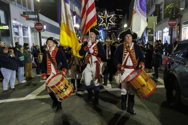 Drummers walk down the street as part of the march to the water to reenact the historic tea tossing.