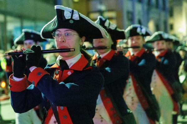 Members of the Fife and Drum Corps play the flute as they march down the street to the wharf on Saturday, Dec. 16.