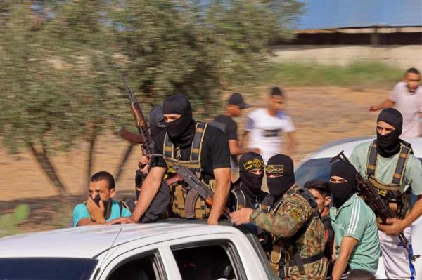 Hamas fighters in masks and camo riding on the back of a truck at high speed headed toward the Israel border on Oct. 7.