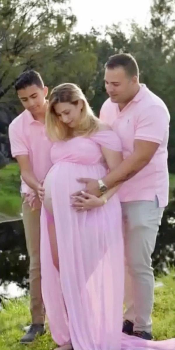 A very pregnant Irina Garcia with her husband and son, all wearing pink, in a family portrait.