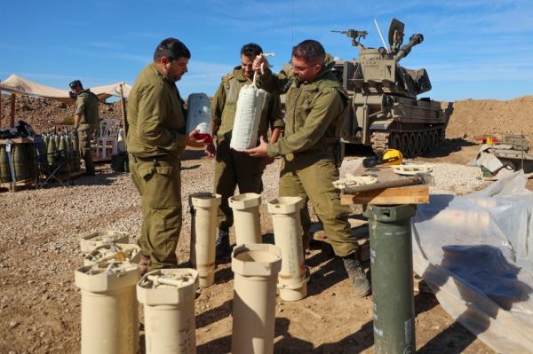 Israeli soldiers prepare munitions near a self-propelled artillery howitzer in southern Israel.