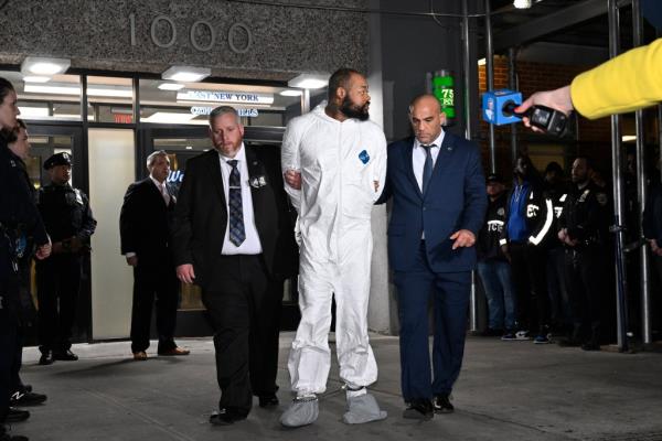 The alleged killer in white jumpsuit with his hands cuffed behind him, is taken to court.