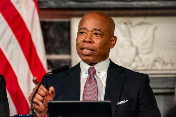 Mayor Eric Adams speaking at a lectern, with an American flag behind him.