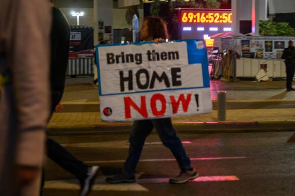 Protesters march through the streets near a clock displaying 69 days in captivity.